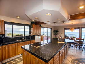 Kitchen with a center island, brown cabinets, white dishwasher, hanging light fixtures, and light tile patterned floors