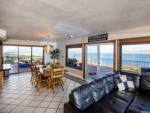 Dining space featuring plenty of natural light, light tile patterned floors, a textured ceiling, a chandelier, and a water view