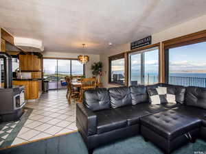 Living area with a water view, a wood stove, light tile patterned floors, a chandelier, and a textured ceiling