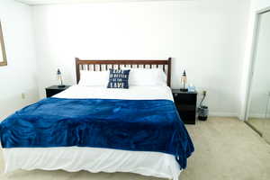 Bedroom with light colored carpet and a closet