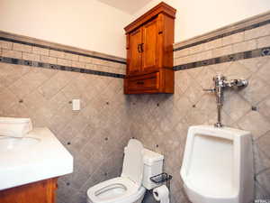 Half bath with tile walls, vanity, and a wainscoted wall