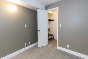 Unfurnished bedroom with light colored carpet and baseboards