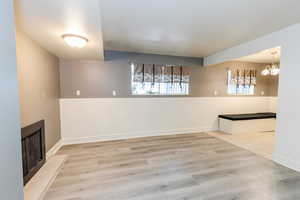 Unfurnished dining area with light wood-type flooring, a chandelier, and a fireplace
