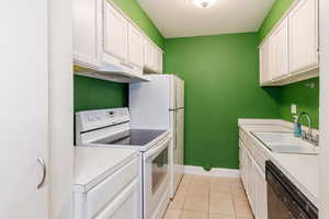 Kitchen featuring white appliances, white cabinets, light countertops, and light tile patterned flooring