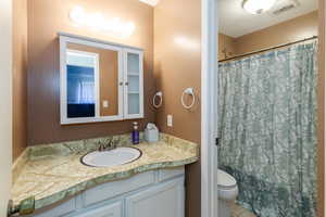 Bathroom featuring vanity, shower / bath combo, and tile patterned flooring