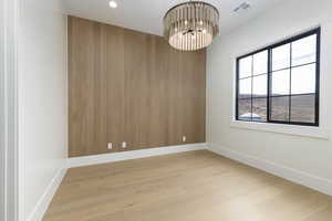 Spare room featuring light wood finished floors, a chandelier, and recessed lighting
