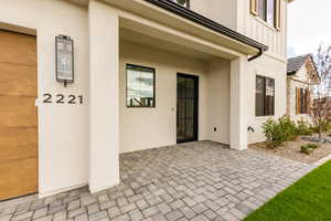 View of exterior entry featuring brick siding, stucco siding, board and batten siding, and covered porch