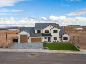 Modern farmhouse with stone siding, decorative driveway, a front lawn, board and batten siding, and a garage