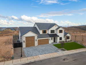 Modern farmhouse style home featuring stone siding, decorative driveway, stucco siding, a garage, and a mountain view