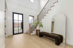 Foyer entrance featuring light wood finished floors, stairs, and a high ceiling
