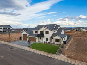 Modern inspired farmhouse featuring stone siding, a garage, and driveway