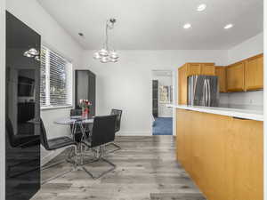 Dining area with healthy amount of natural light, light wood-style flooring, recessed lighting, and a chandelier