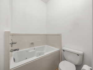 Bathroom featuring a whirlpool tub and toilet