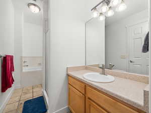 Full bath featuring vanity, a garden tub, a shower stall, and light tile patterned flooring