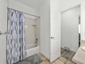 Full bathroom with shower / bath combo with shower curtain, light tile patterned floors, and vanity