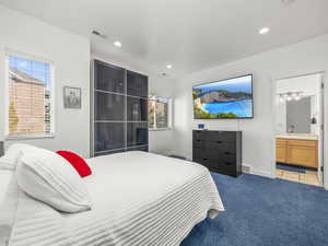 Carpeted bedroom with multiple windows, ensuite bath, and recessed lighting
