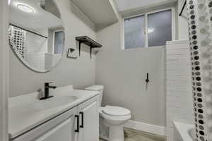 Full bath featuring vanity, shower / tub combo with curtain, and light wood finished floors