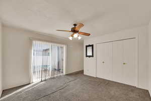 Unfurnished bedroom featuring carpet, ceiling fan, a closet, access to outside, and a textured ceiling