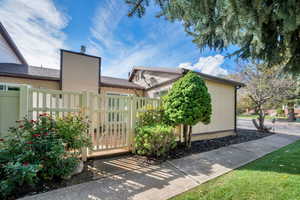 View of side of property featuring a gate and a shingled roof