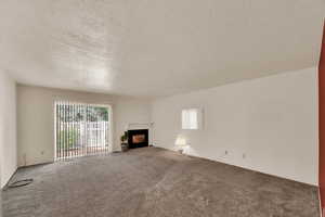 Unfurnished living room with a textured ceiling, a fireplace, and carpet