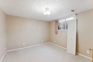 Unfurnished bedroom with light carpet and a textured ceiling