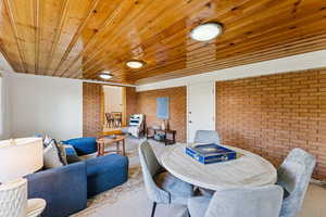 Dining area with brick wall, wooden ceiling, and crown molding