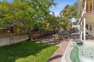 Fenced backyard featuring a patio and a hot tub