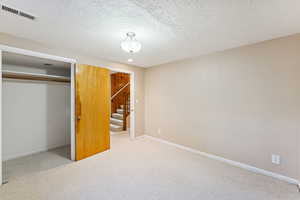 Unfurnished bedroom with carpet flooring, a textured ceiling, and a closet