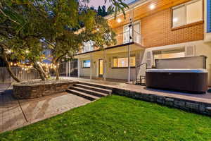 Rear view of house with a hot tub, a patio, a balcony, and brick siding