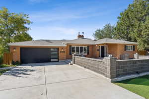 View of front of property with a fenced front yard, brick siding, concrete driveway, and a garage