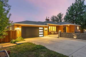 View of front facade with brick siding, concrete driveway, an attached garage, and a chimney
