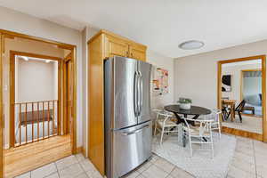 Kitchen with freestanding refrigerator, light tile patterned flooring, and light brown cabinetry