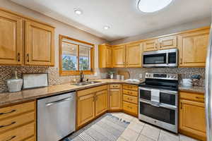 Kitchen with appliances with stainless steel finishes, backsplash, light tile patterned floors, light stone countertops, and recessed lighting