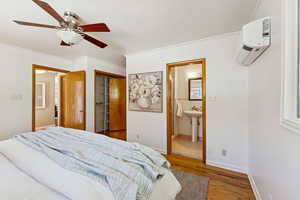 Bedroom featuring ornamental molding, wood finished floors, a closet, ceiling fan, and a wall unit AC