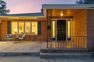 Exterior entry at dusk featuring brick siding and a porch
