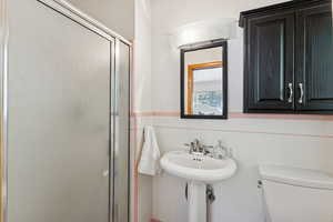 Bathroom featuring a shower stall, tile walls, and a wainscoted wall