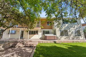 View of front of property with a patio area, a hot tub, a balcony, and a front yard