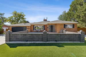View of front facade featuring a fenced front yard, brick siding, concrete driveway, and a chimney