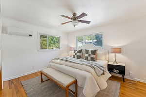 Bedroom featuring crown molding, light wood-style flooring, a ceiling fan, and a wall mounted AC