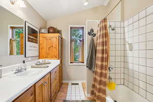 Full bath with shower / bath combo, vanity, light tile patterned floors, and vaulted ceiling