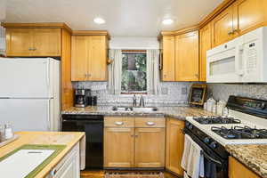 Kitchen featuring white appliances, backsplash, butcher block countertops, recessed lighting, and brown cabinetry