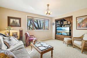 Carpeted living room featuring a chandelier and baseboards
