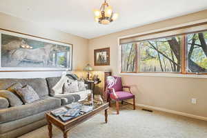 Carpeted living area with a chandelier and baseboards
