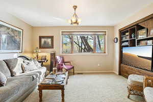 Carpeted living room with baseboards and a chandelier
