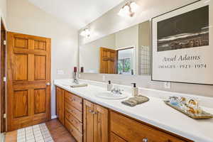 Bathroom featuring double vanity, light tile patterned floors, and lofted ceiling