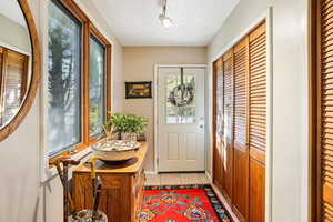 Doorway to outside with tile patterned flooring and rail lighting