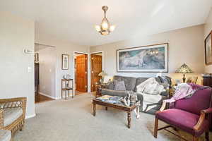 Carpeted living room featuring baseboards and a chandelier