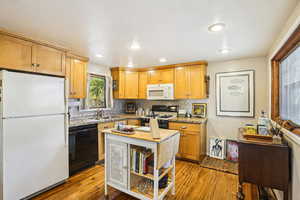 Kitchen featuring white appliances, light wood finished floors, decorative backsplash, recessed lighting, and light stone counters