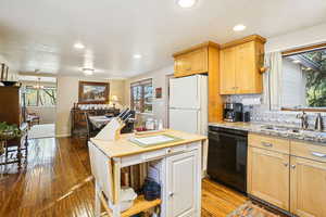 Kitchen featuring backsplash, freestanding refrigerator, dishwasher, light wood-style floors, and recessed lighting