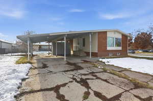 View of front of property with a carport, driveway, entry steps, and brick siding